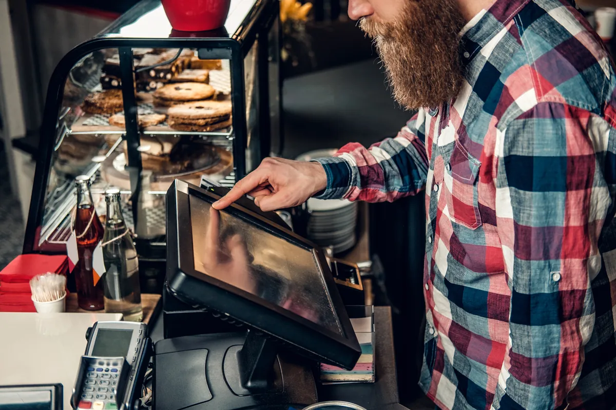 A shopkeeper ringing up an order on a counter-top till